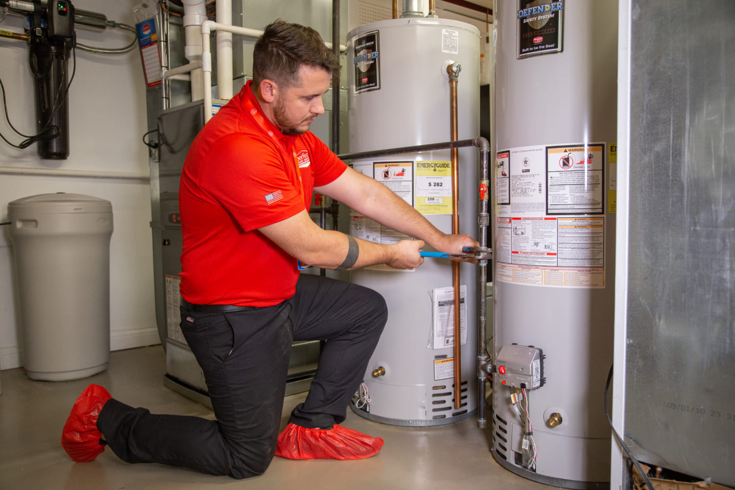 Perfect Home Service employee installing a conventional water heater in basement