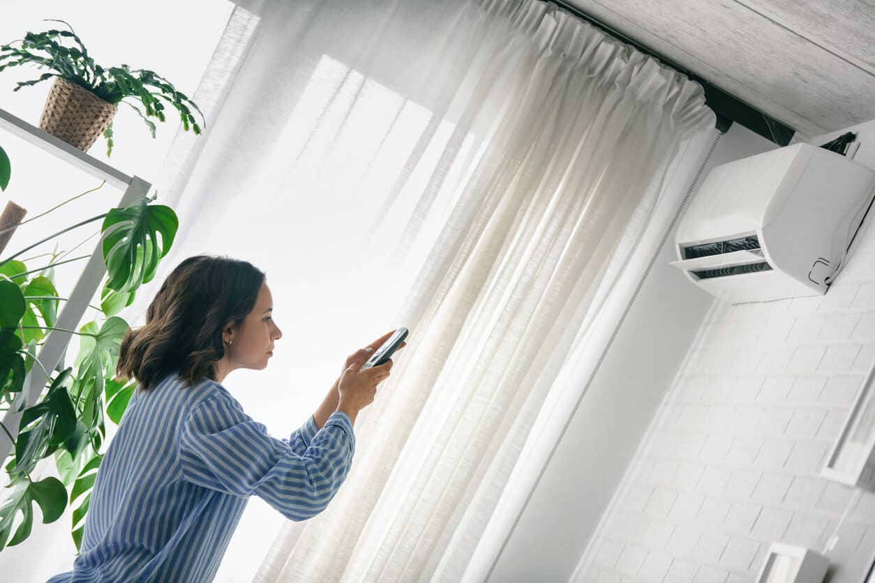 Woman standing in front of her ductless heating and cooling system